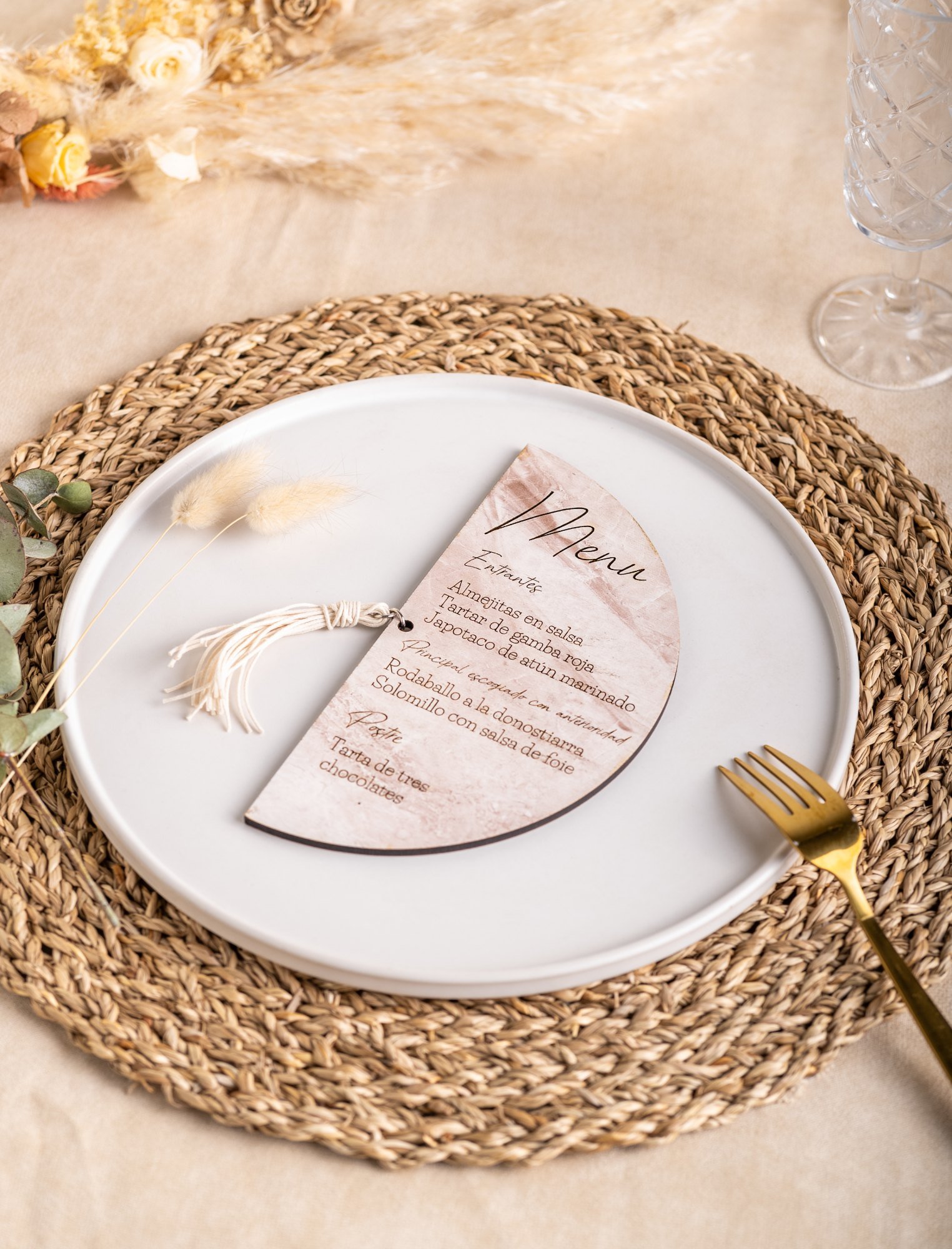 Menú de boda de madera en forma de media luna con borla sobre el plato